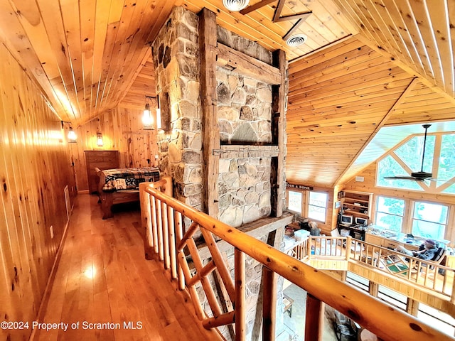 hall featuring hardwood / wood-style floors, wooden walls, vaulted ceiling, and wooden ceiling