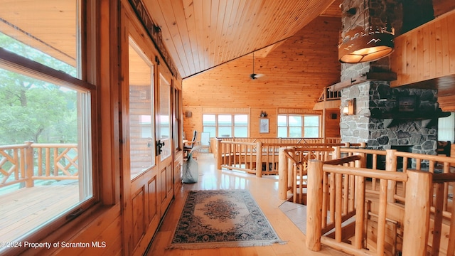 interior space featuring wooden ceiling, light hardwood / wood-style flooring, high vaulted ceiling, wooden walls, and a water view