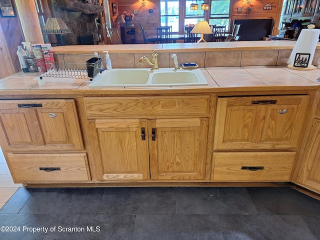 interior space featuring tile countertops, sink, and wooden walls