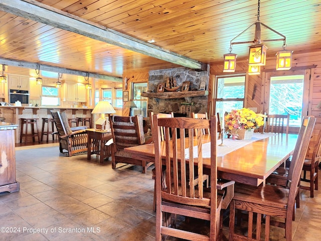 dining area with beamed ceiling, wooden ceiling, tile patterned floors, and wooden walls