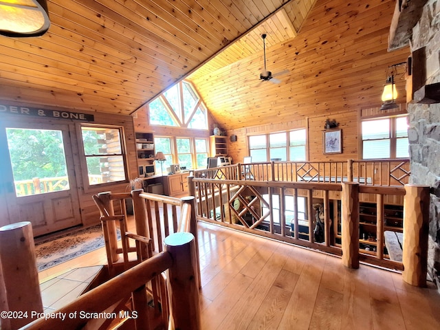 dining room featuring wooden ceiling, high vaulted ceiling, wooden walls, light hardwood / wood-style flooring, and ceiling fan