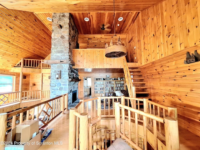 interior space with wood walls, wood ceiling, high vaulted ceiling, and light hardwood / wood-style flooring