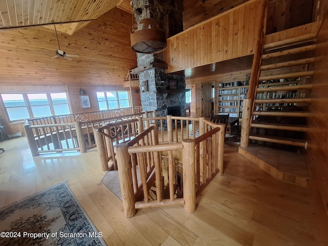 interior space with wood walls, high vaulted ceiling, light wood-type flooring, and ceiling fan