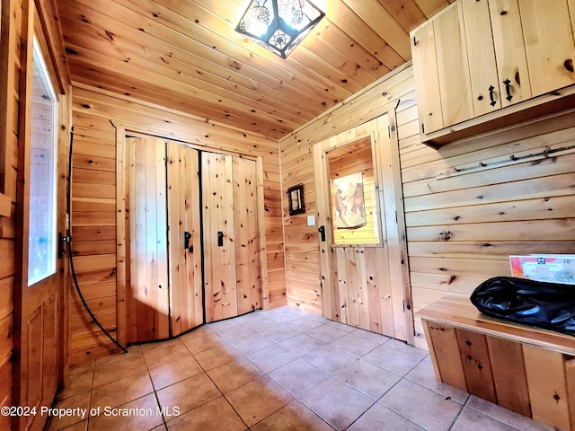 interior space with wood walls, light tile patterned floors, and wood ceiling