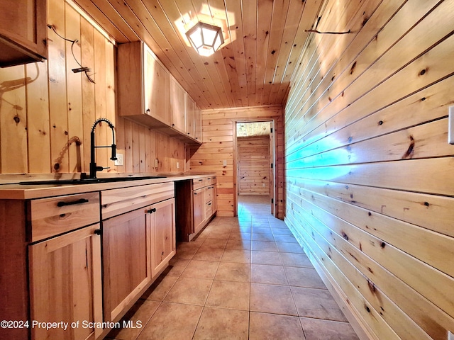 interior space featuring light tile patterned flooring, sink, wooden walls, and wood ceiling