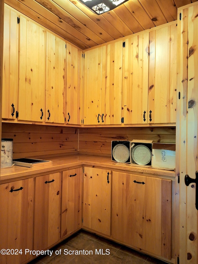 kitchen featuring dark tile patterned flooring and wooden walls