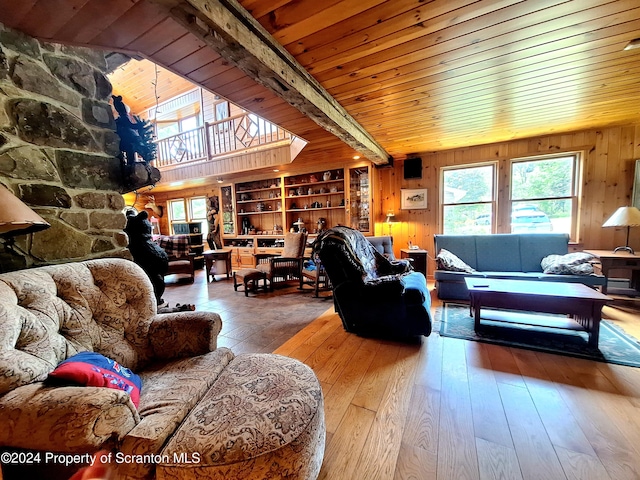 living room with beam ceiling, built in features, wood walls, wood-type flooring, and wood ceiling