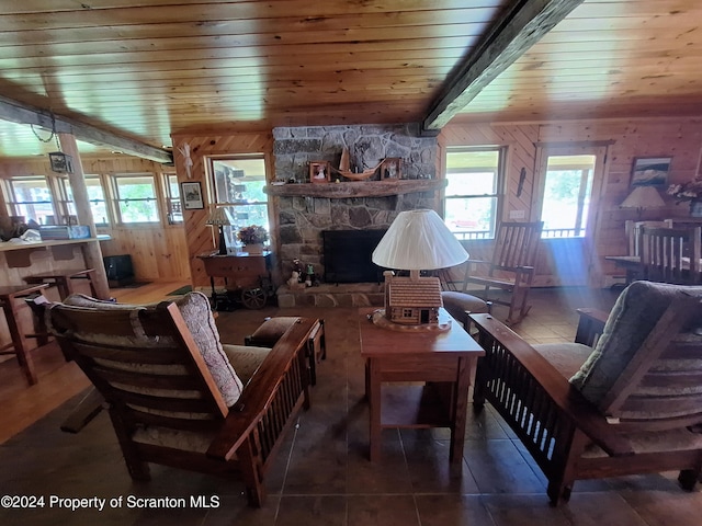 living room with wooden walls, tile patterned flooring, a fireplace, beam ceiling, and wood ceiling