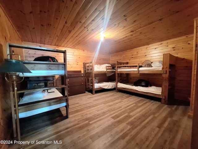 bedroom with wooden walls, hardwood / wood-style floors, and wood ceiling