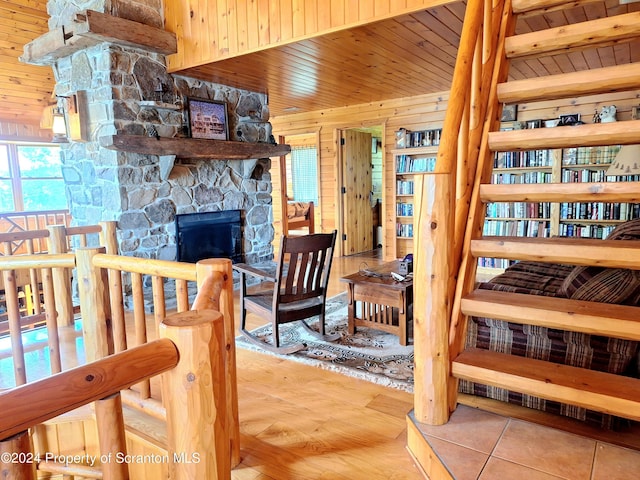 interior space featuring a stone fireplace, wooden ceiling, and wood walls