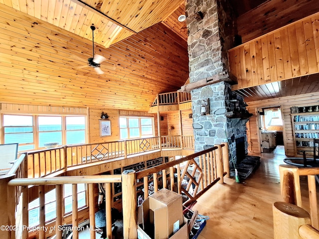 hall with a water view, wood walls, high vaulted ceiling, and wood ceiling