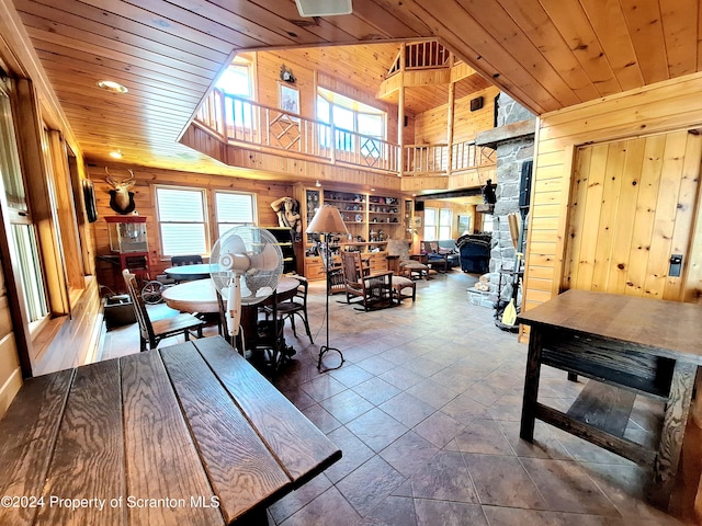 dining area featuring a towering ceiling, built in features, wooden walls, and wood ceiling