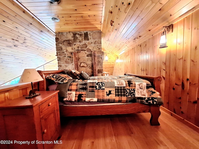 bedroom with hardwood / wood-style flooring, vaulted ceiling, wooden walls, and wood ceiling