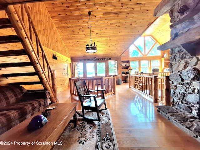 living room featuring wooden walls, high vaulted ceiling, wood ceiling, and light wood-type flooring