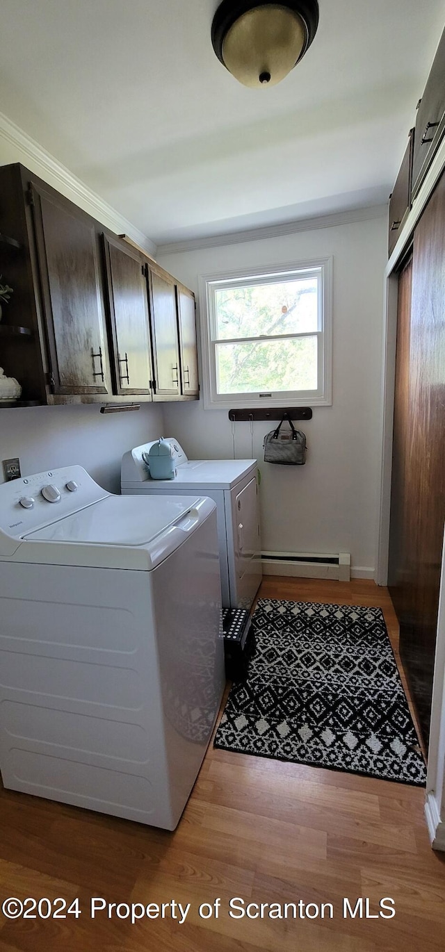 washroom featuring cabinets, crown molding, washing machine and dryer, baseboard heating, and light hardwood / wood-style floors