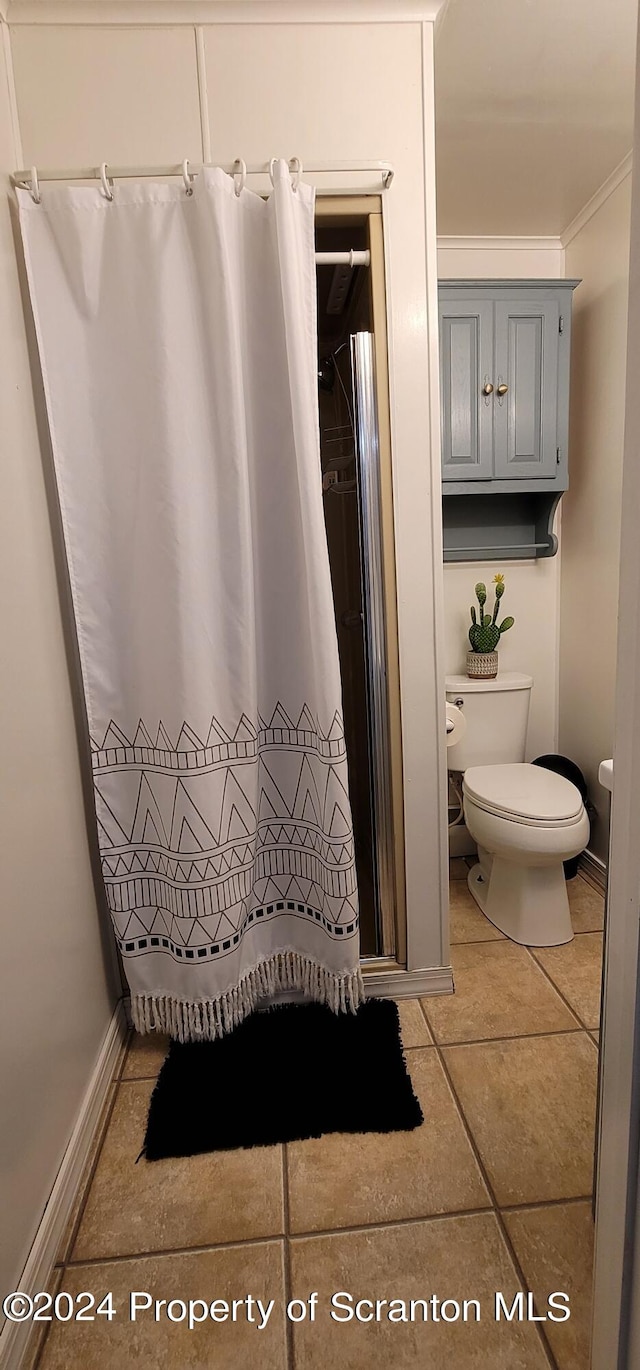 bathroom with tile patterned flooring, toilet, curtained shower, and ornamental molding