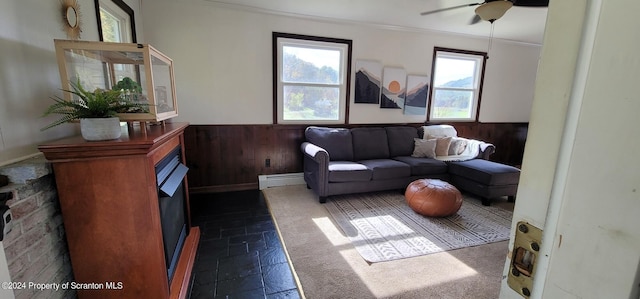 living room featuring ceiling fan, wood walls, ornamental molding, and baseboard heating