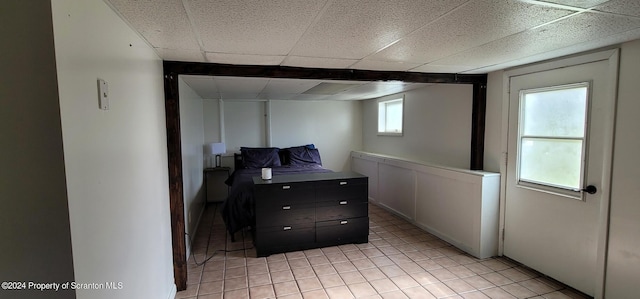 basement with a drop ceiling and light tile patterned flooring