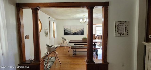 corridor with decorative columns, hardwood / wood-style flooring, and an inviting chandelier