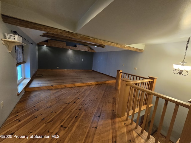 additional living space featuring beam ceiling, dark hardwood / wood-style floors, and a notable chandelier