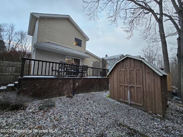 back of house with a storage shed and a deck