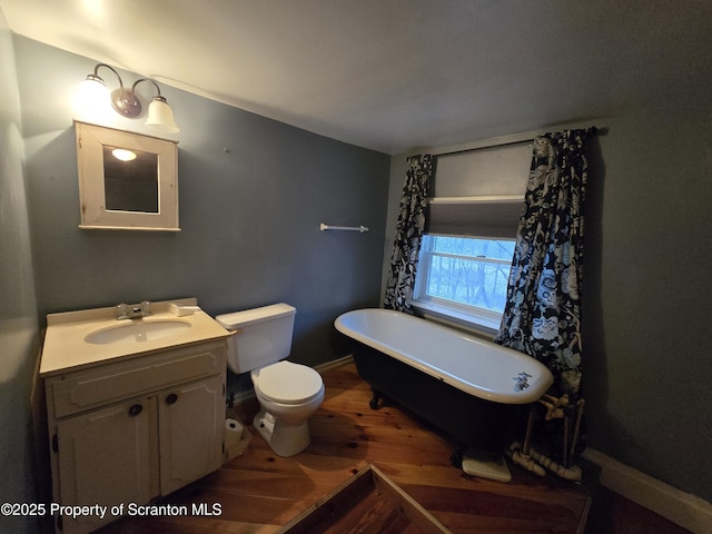 bathroom with a bathing tub, toilet, vanity, and hardwood / wood-style flooring