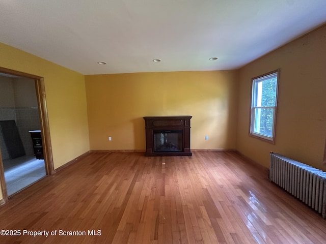 439 Old Union Rd, Equinunk, PA 18417 - unfurnished living room featuring a glass covered fireplace, radiator heating unit, light wood-style floors, and recessed lighting