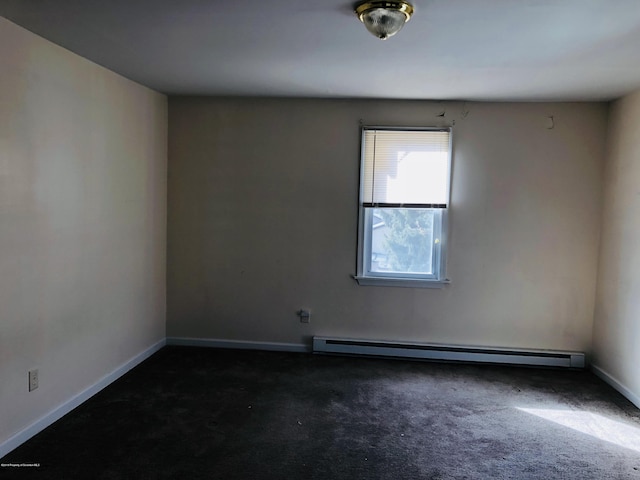 spare room with baseboards, dark carpet, and baseboard heating