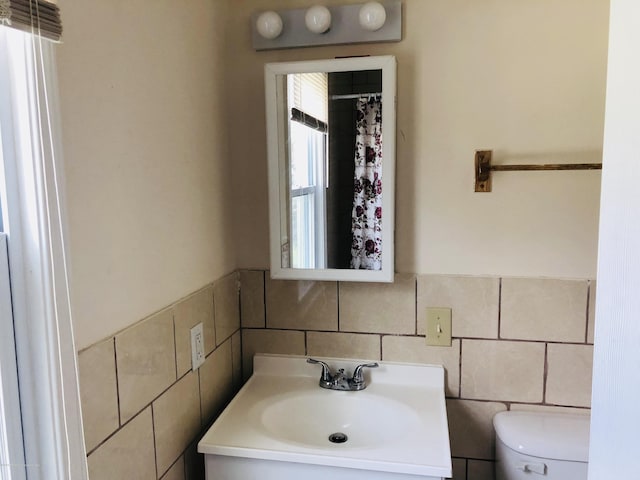 bathroom featuring toilet, tile walls, and vanity