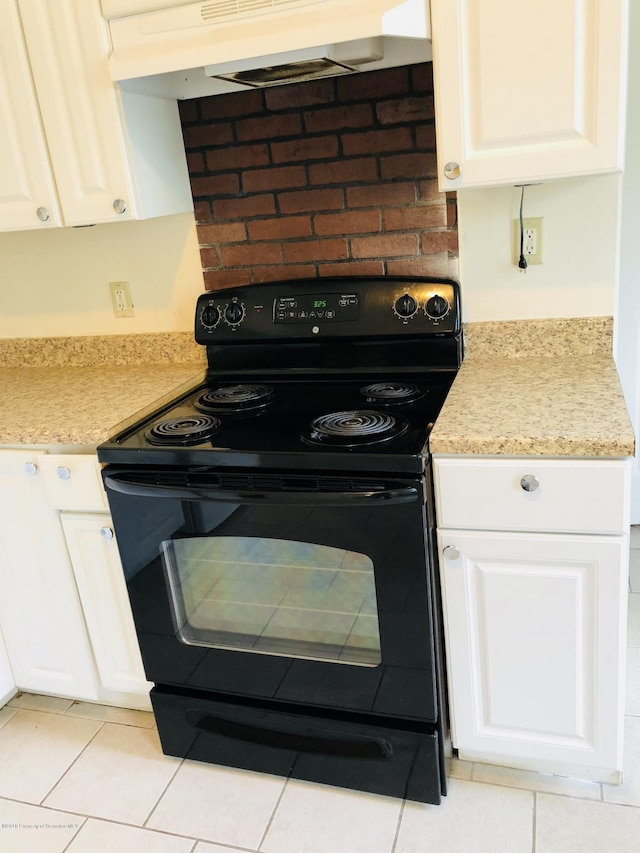 kitchen with black electric range, under cabinet range hood, white cabinets, and light countertops