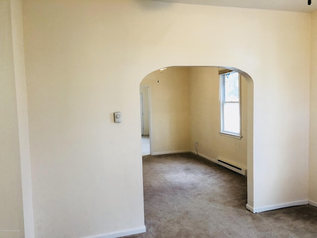 empty room with a baseboard heating unit, carpet, arched walkways, and baseboards