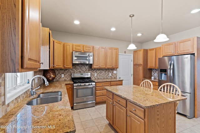 kitchen featuring stainless steel appliances, a center island, sink, and light stone countertops