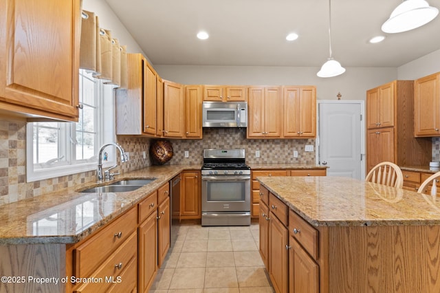 kitchen featuring hanging light fixtures, light tile patterned floors, a kitchen island, appliances with stainless steel finishes, and sink