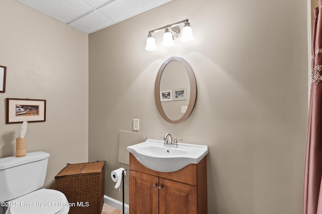 bathroom featuring a paneled ceiling, vanity, and toilet