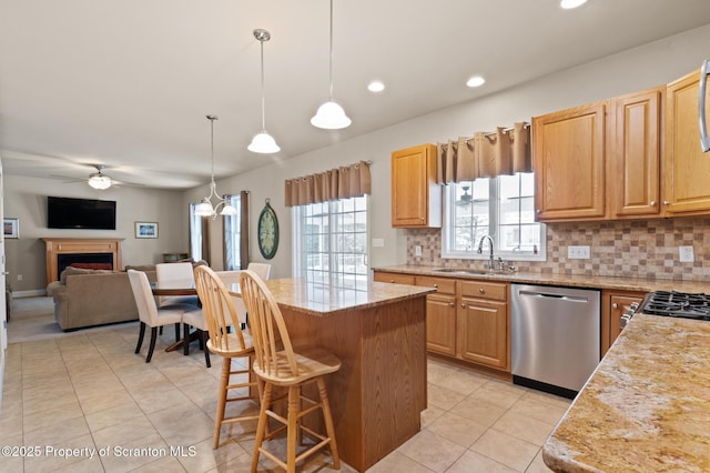 kitchen featuring hanging light fixtures, a center island, sink, stainless steel dishwasher, and tasteful backsplash