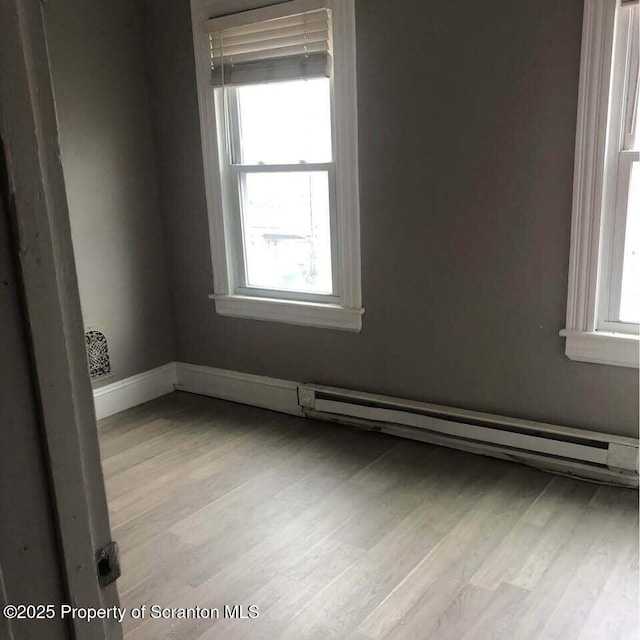 spare room with baseboard heating and light wood-type flooring