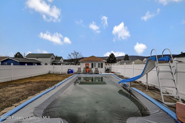 view of swimming pool with a fenced in pool, a water slide, a fenced backyard, and an outdoor structure