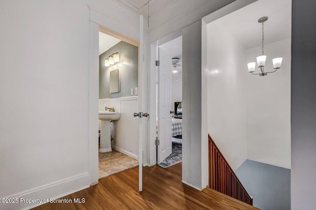 corridor with wainscoting, wood finished floors, and an inviting chandelier