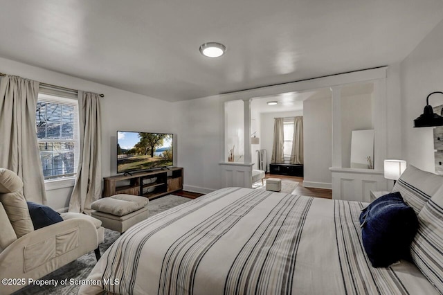 bedroom with multiple windows, baseboards, and wood finished floors