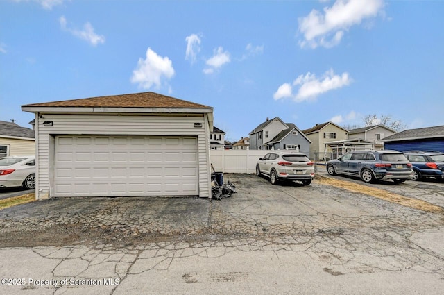 exterior space with a detached garage, fence, and a residential view