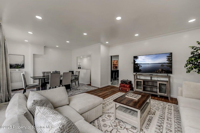 living area featuring baseboards, ornamental molding, wood finished floors, and recessed lighting