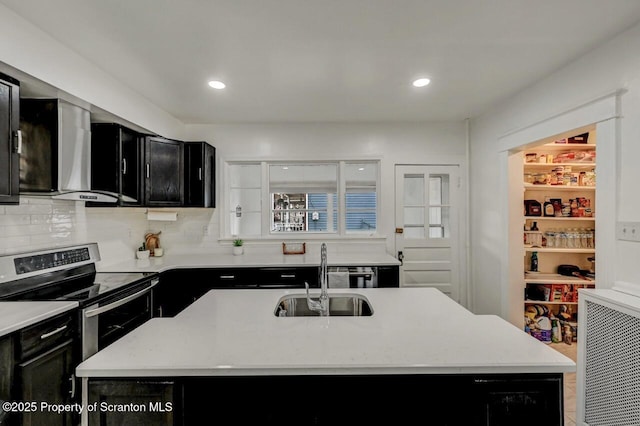 kitchen with a sink, light countertops, dark cabinetry, backsplash, and stainless steel range with electric stovetop