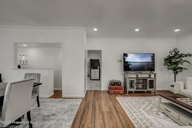 living area featuring baseboards, ornamental molding, wood finished floors, and recessed lighting