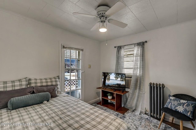 bedroom featuring radiator, ceiling fan, multiple windows, and ornamental molding