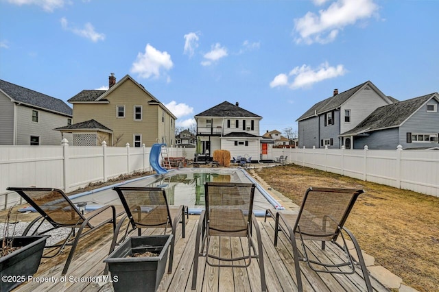 wooden terrace with outdoor dining space, a fenced backyard, and a residential view