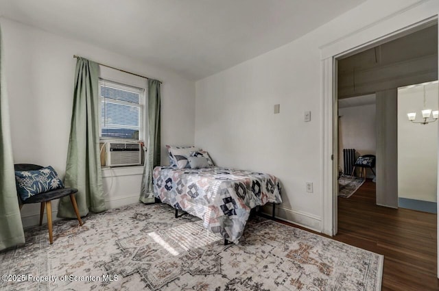 bedroom featuring cooling unit, a notable chandelier, baseboards, and wood finished floors