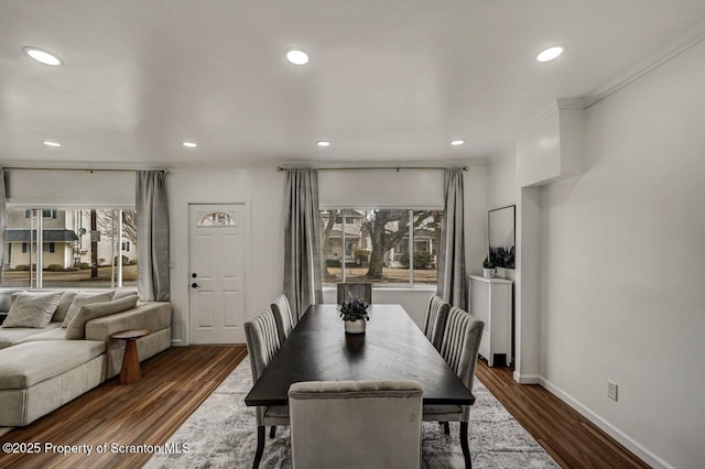 dining room with ornamental molding, dark wood-style flooring, a healthy amount of sunlight, and baseboards