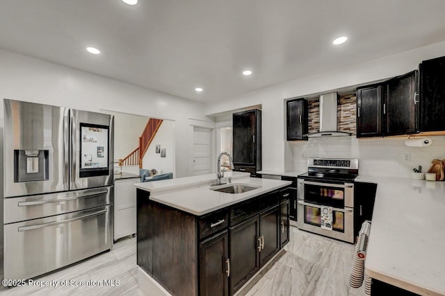 kitchen with light countertops, decorative backsplash, appliances with stainless steel finishes, a sink, and wall chimney exhaust hood