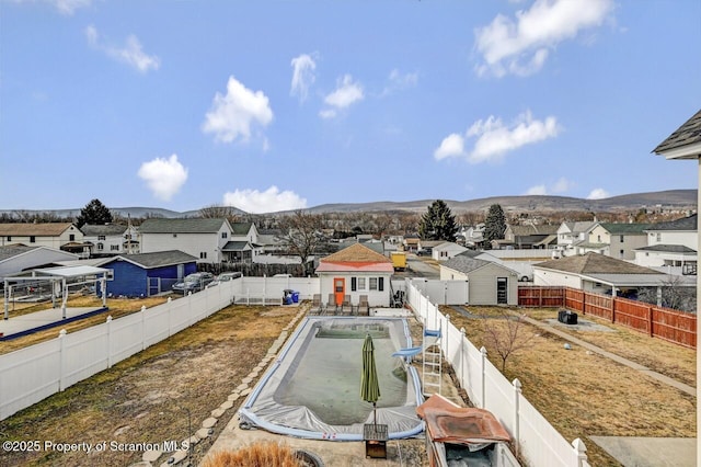 exterior space with a residential view, a fenced backyard, and a mountain view