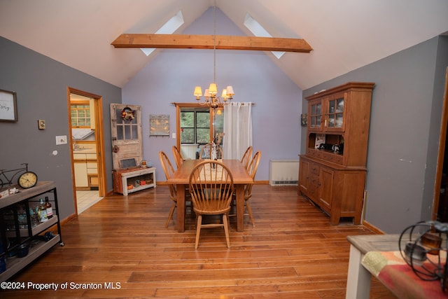 dining space with light wood-type flooring, radiator, a notable chandelier, and vaulted ceiling with skylight